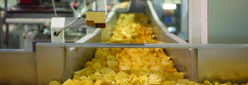 Gula chips på ett löpande band, i industrimiljö 
