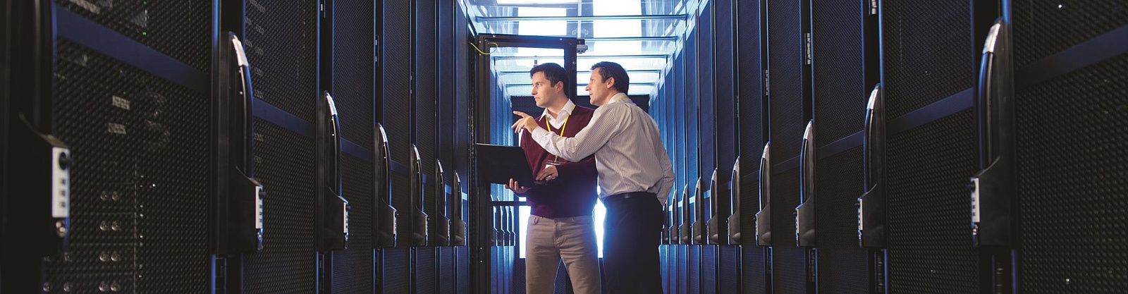 Två män diskuterar mellan två långa rader av dataservrar 