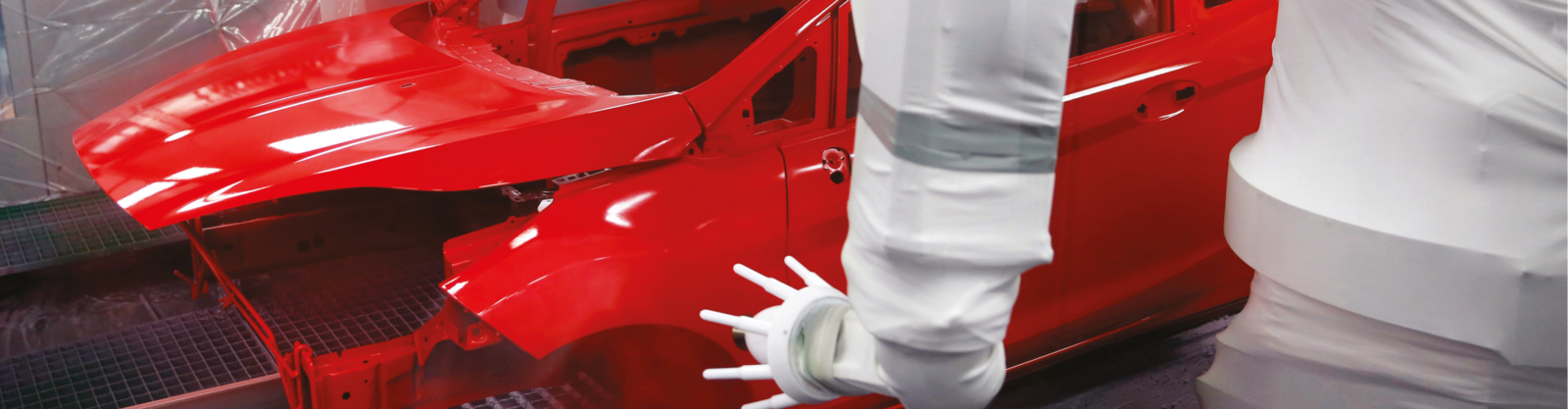 En högglansig rödfärgad bilkaross står i ett vitklätt rum 