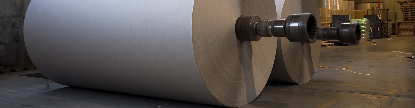 Ett foto i industrimiljö på två stora valsar med gigantiska vita pappersrullar 